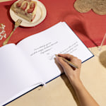 A hand signing an open guest book. 