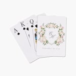 A stack of playing cards customized with a floral wedding monogram. 