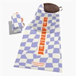 A personalized beach towel printed with a purple checkered pattern and a name. 