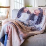 A photo blanket featuring two sisters laughing.