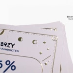 Een close-up van een visitekaartje met logo en tekst in gouden foliedruk.