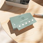 Uma pilha de cartões de fidelização de um spa sobre uma mesa de madeira, com uma caneta ao lado.