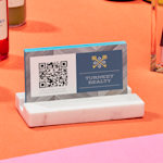 Um suporte de cartões de visita em mármore com cartões de visita com código QR de alguém chamado Raúl Benítez.