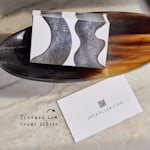 Uma pilha de cartões de visita mate numa taça de madeira, com uma nota a destacar a textura suave e acetinada.