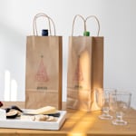2 brown kraft wine bags with Christmas tree images on them.