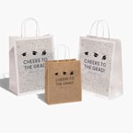 A custom paper bag printed with a kids’ shop logo, set beside a sheet of matching stickers.  