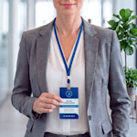 An ID badge for a professional event or corporate use, worn on a blue lanyard.
