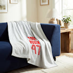 A white sweatshirt blanket printed with an athlete’s name and number. 