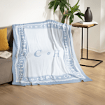 A custom monogrammed blanket draped over a living room couch. 