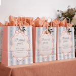 A table of brown party bags at a birthday, decorated with flowers and ribbon.