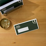 Ett företagskuvert ligger på ett skrivbord och har en logotyp i det övre vänstra hörnet och ett adressfält synligt.