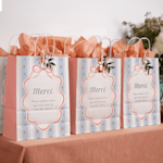 Une table de sacs de fête marrons à un anniversaire, décorés de fleurs et de rubans.