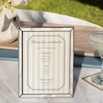 Un menu de cocktails personnalisé à motif rayé, présenté dans un cadre élégant. 