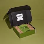 Une boîte pour envoi postal entièrement imprimée, contenant du papier plissé et un paquet de café. Parmi les avantages mis en avant : des prix imbattables, des délais de production rapides, des couleurs éclatantes à l’impression et la livraison offerte.