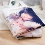 Eine quadratisch gefaltete, personalisierte Decke mit dem Foto zweier kleiner Mädchen.