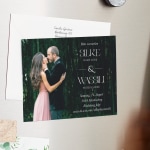 Ein an einem Kühlschrank haftender Save-the-Date-Magnet mit dem Foto eines sich umarmenden Hochzeitspaares.