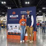 A man and a woman standing in front of a home renovation pop-up display at a tradeshow.