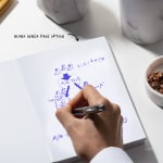 A person sketching a flowchart in a perfect bound notebook with blank inner pages.