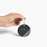 A person holding up a Christmas ornament, measuring 7 x 7 cm.