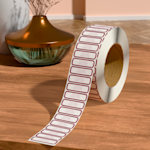 A personalised return address roll label placed on a table, next to a vase.