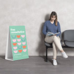 An image of a woman in a blue shirt reading while sitting in a waiting room, with a Corrugated A-frame sign promoting free consultations with a dentist.