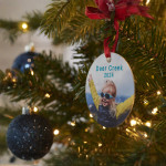 A custom ornament on a Christmas tree featuring a photo of a little girl in sunglasses.