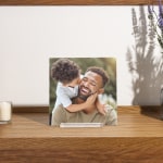 A photo tile printed with a picture of a dad and his son, displayed on a wood tabletop.