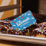 A playful blue business card resting on a tray of donuts.