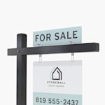A for sale top rider on a black colonial post with a real estate yard sign hanging below.