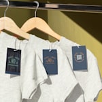 Plastic hang tags on shirts hanging on hangers.