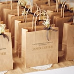 A table of brown party bags at a birthday, decorated with flowers and ribbon.