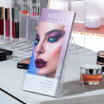 Glittery purple foil accent rack cards from a make up artist being displayed on the counter of a beauty salon.