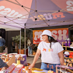 A close up of a handmade goods store set up underneath a canopy tent in an outdoor market.