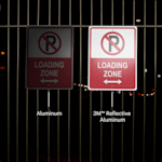 2 parking signs show hanging on a fence at night time.