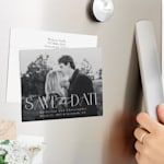 A save the date magnet displayed on the fridge, featuring a couple’s black and white engagement photo. 
