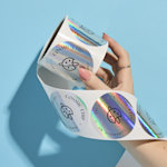 Several boxes of cookies with holographic circle labels from a roll placed on top.  