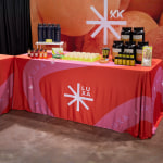 trade show table for a wellness brand with product samples, water bottles and custom branded rectangular tablecloth