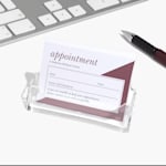 An acrylic business card holder holding appointment reminder cards for a medical clinic.