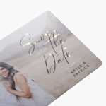A custom save the date card featuring a photo of a couple and embossed foil detailing.