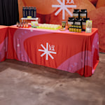 trade show table for a wellness brand with product samples, water bottles and custom branded rectangular tablecloth