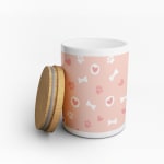 A pink and white treat jar personalised with dog bones, paw prints and hearts.