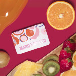 A spot UV business card for a juice cafe rests on a table with fresh-cut fruits.