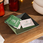 A stack of square, matte-finish business cards for a home goods company, resting in a bowl.