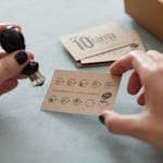 A kraft business card used as a loyalty card for a coffee shop featuring a hand poised to stamp the card.