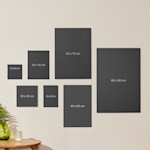 Assorted custom photo canvases hanging on a wall, labelled by their sizes.