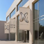A building exterior featuring multiple custom wall-mounted banners promoting a retail business.