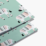 Custom notebooks with playful zebra pattern design on mint green background showing edge binding detail.