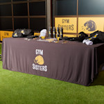 tradeshow rectangle table with branded tablecloth displaying branded apparel and promotional products for a gym business