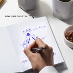 A person sketching a flowchart in a perfect bound notebook with blank inner pages.