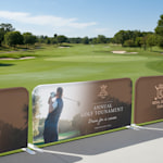 Event barriers promoting a golf event, displayed outdoors.